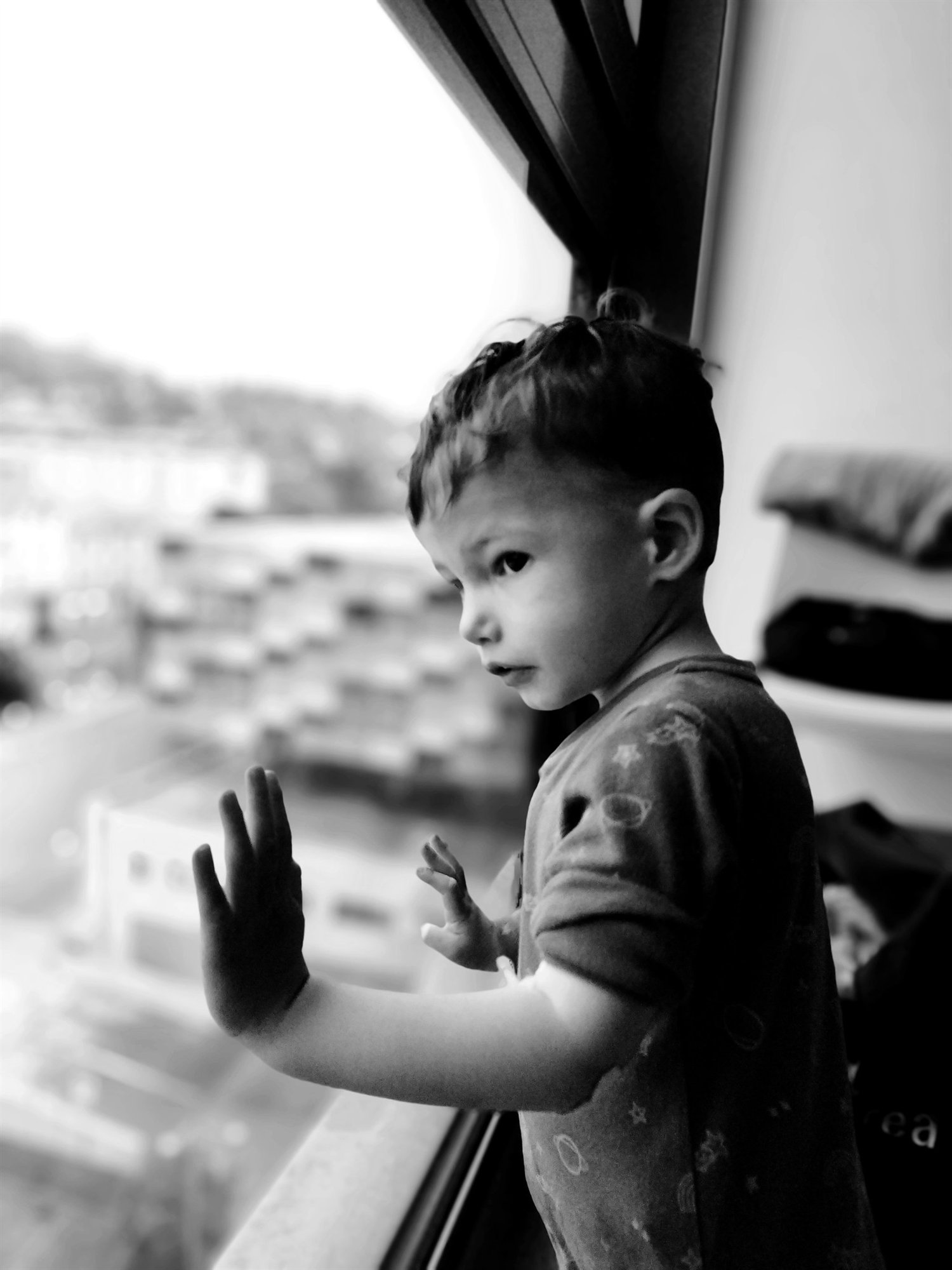 Bambino con la mano appoggiata al vetro di una finestra, in bianco e nero